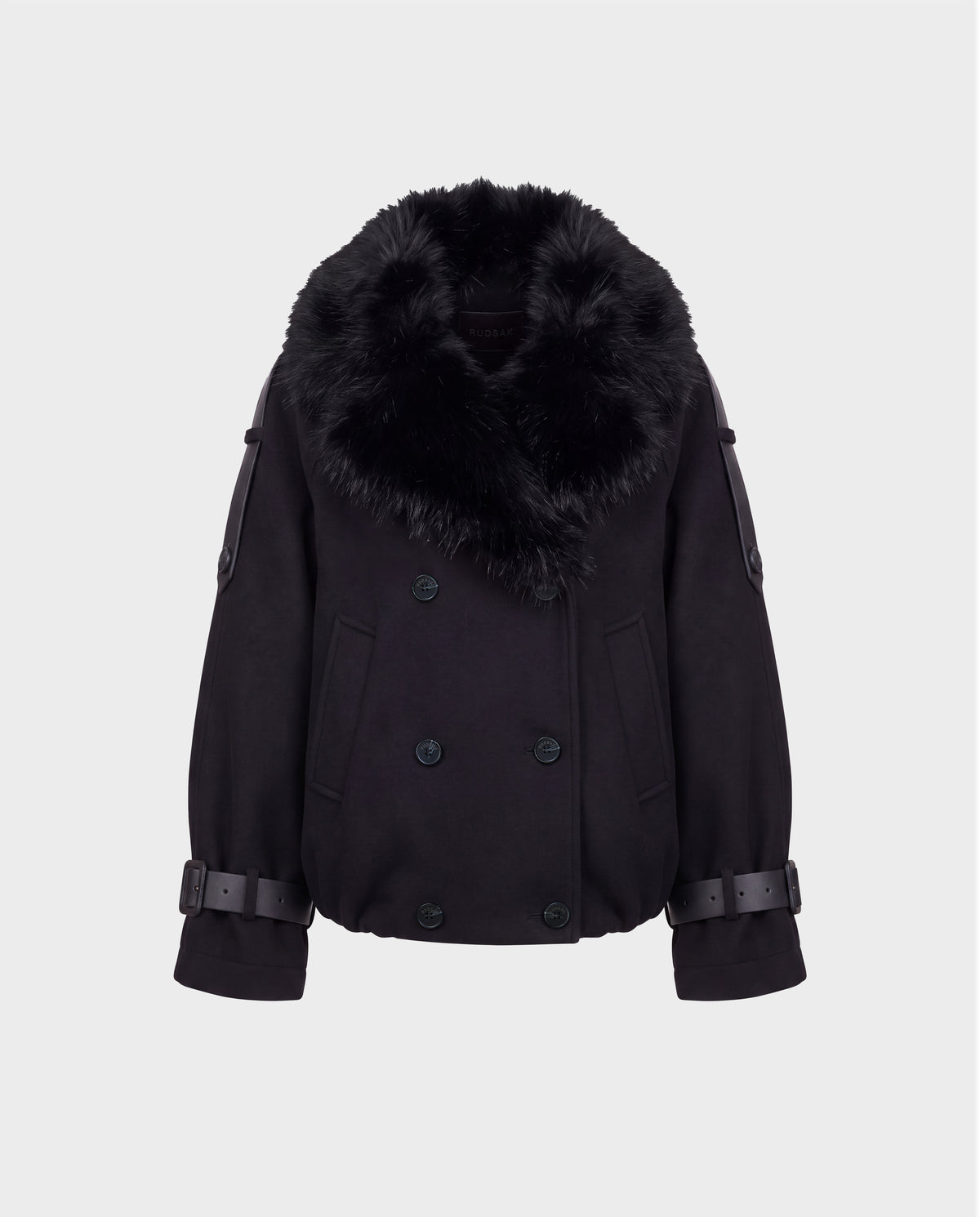 The Rudsak MAEMI - 8126985 Black jacket features a double-breasted front with wide, removable faux fur collar, button details, and adjustable buckled sleeve straps. Its boxy fit and modern, luxe aesthetic recall a high-end bomber jacket, showcased here against a plain white background.
