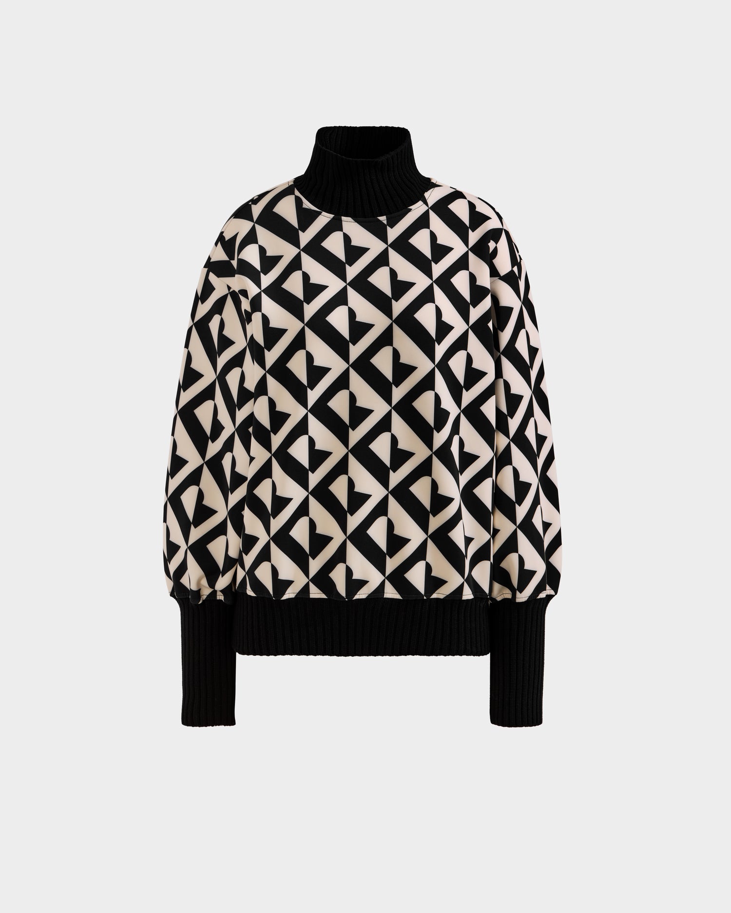 The Rudsak MAGGIE - 8525645 Vanilla Monogram is a women’s long-sleeve ski sweater featuring a black and white geometric heart pattern with ribbed black turtleneck, cuffs, and hem, shown on a plain white background.