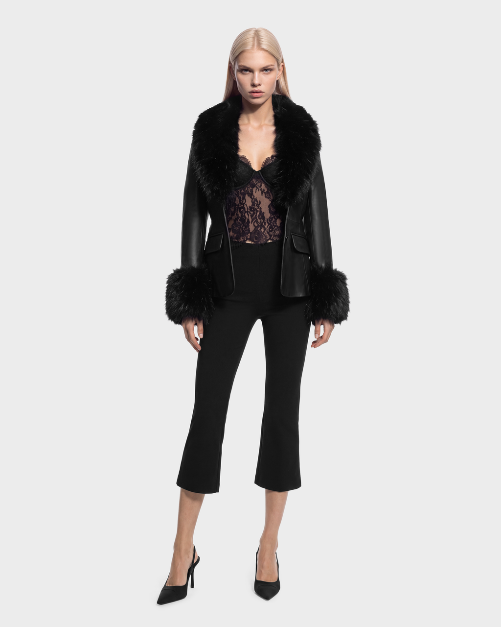 A person wearing a MARILLA - 8126972 Black leather jacket with a black fur collar and cuffs, over a black lace bodysuit and cropped black trousers, paired with black high-heeled pumps.
