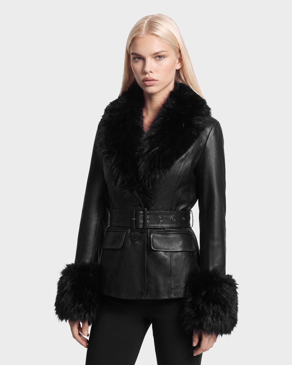 A woman wearing a Rudsak MARILLA - 8126972 Black leather jacket with a belted waist, fur collar, and fur-trimmed cuffs.
