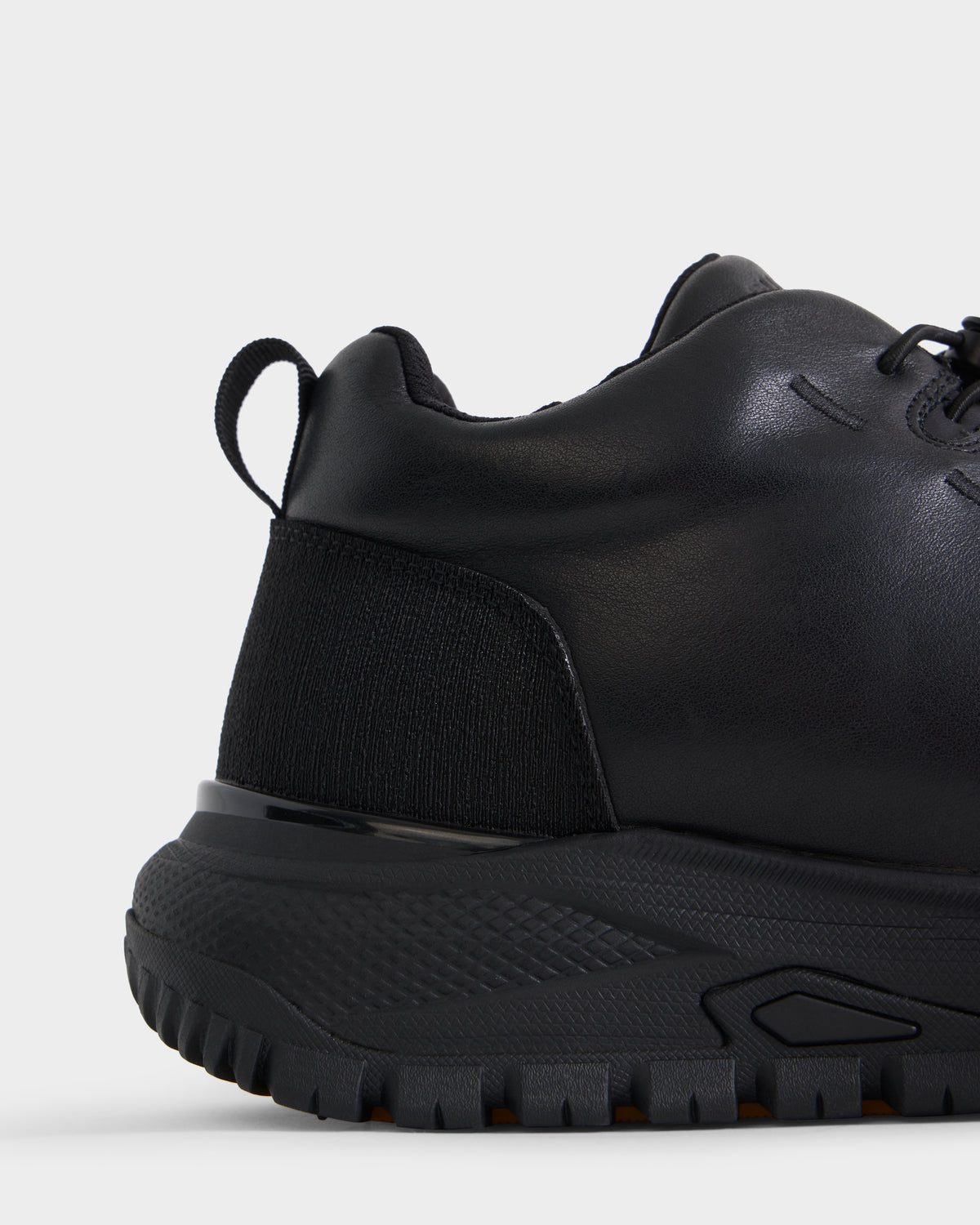 Close-up side view of the Rudsak MAX - 6226502 Black men’s sneaker featuring a textured sole, black laces, and a heel pull tab. The shoe combines smooth and fabric materials with utility-inspired detailing for a sleek athletic style. Set against a plain white background.