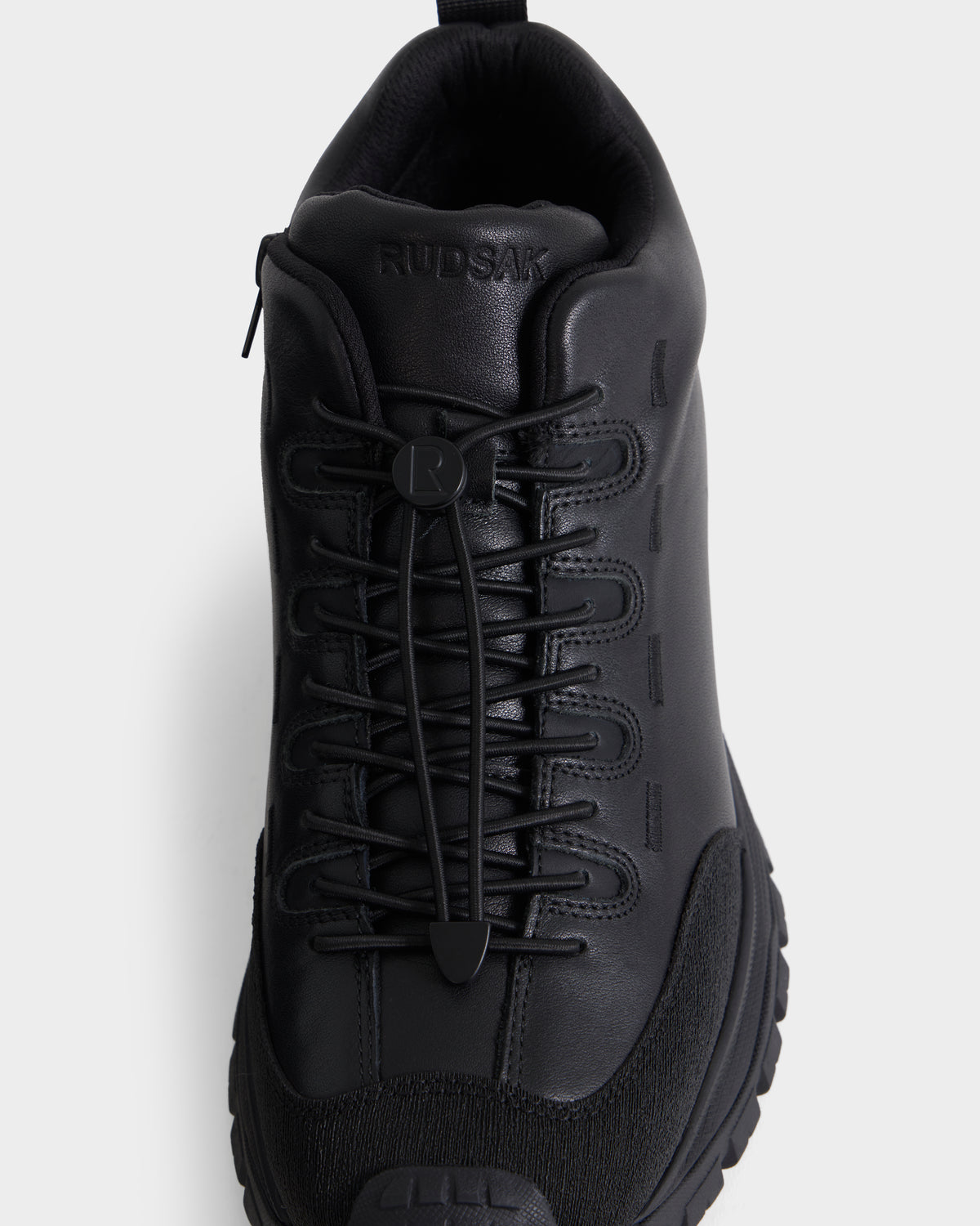 The Rudsak MAX - 6226502 Black sneaker, shown from above against a white background, features a leather upper, chunky sole, distinct toggle lacing system, and utility-inspired details for an athletic look.