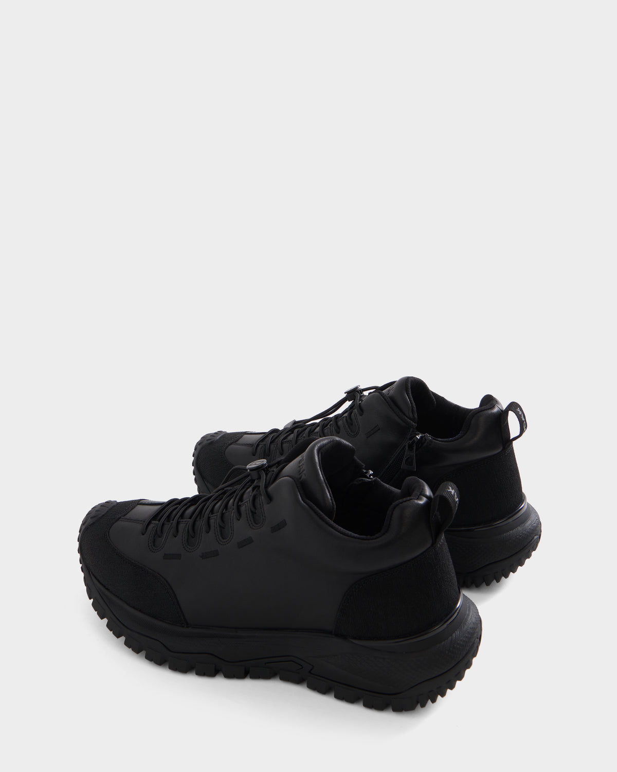 A pair of Rudsak MAX - 6226502 Black men’s sneakers featuring a modern lace-up design, thick textured soles, and utility-inspired detailing, shown from a rear side angle against a plain white background.