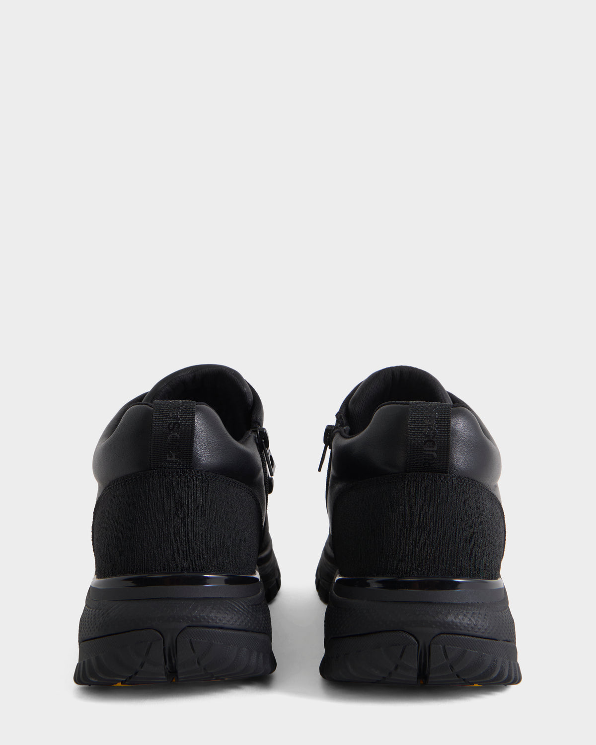 A pair of Rudsak MAX - 6226502 Black men’s sneakers viewed from the back, featuring utility-inspired detailing on the heel and a textured sole against a plain white background.