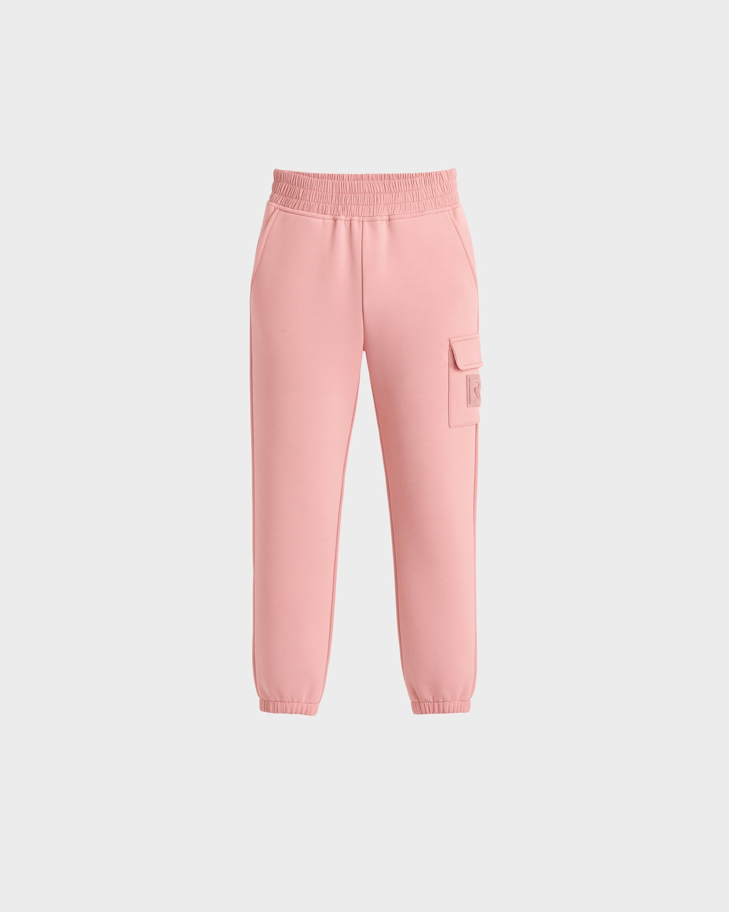 The Rudsak NOOR - 1525004 Light Pink jogger pants feature an elastic waistband, side pockets, a right leg cargo pocket, and elastic ankle cuffs, shown on a plain white background.