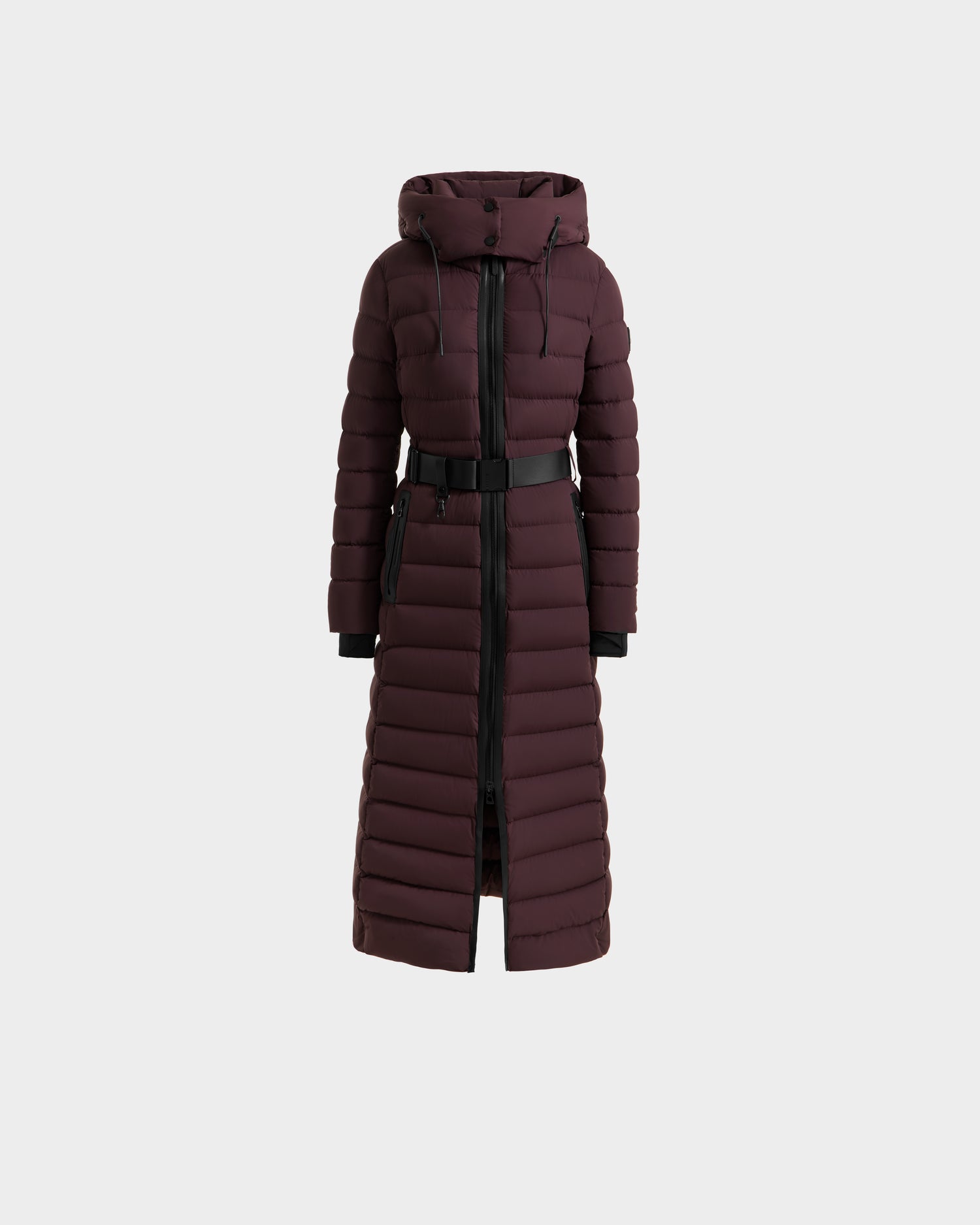 The Rudsak PELIN L - 8124815 Bordeaux is a women's long down puffer coat with a hood, front zipper, black waist belt, and horizontal quilting. This dark maroon winter coat features long sleeves and a below-the-knee length.