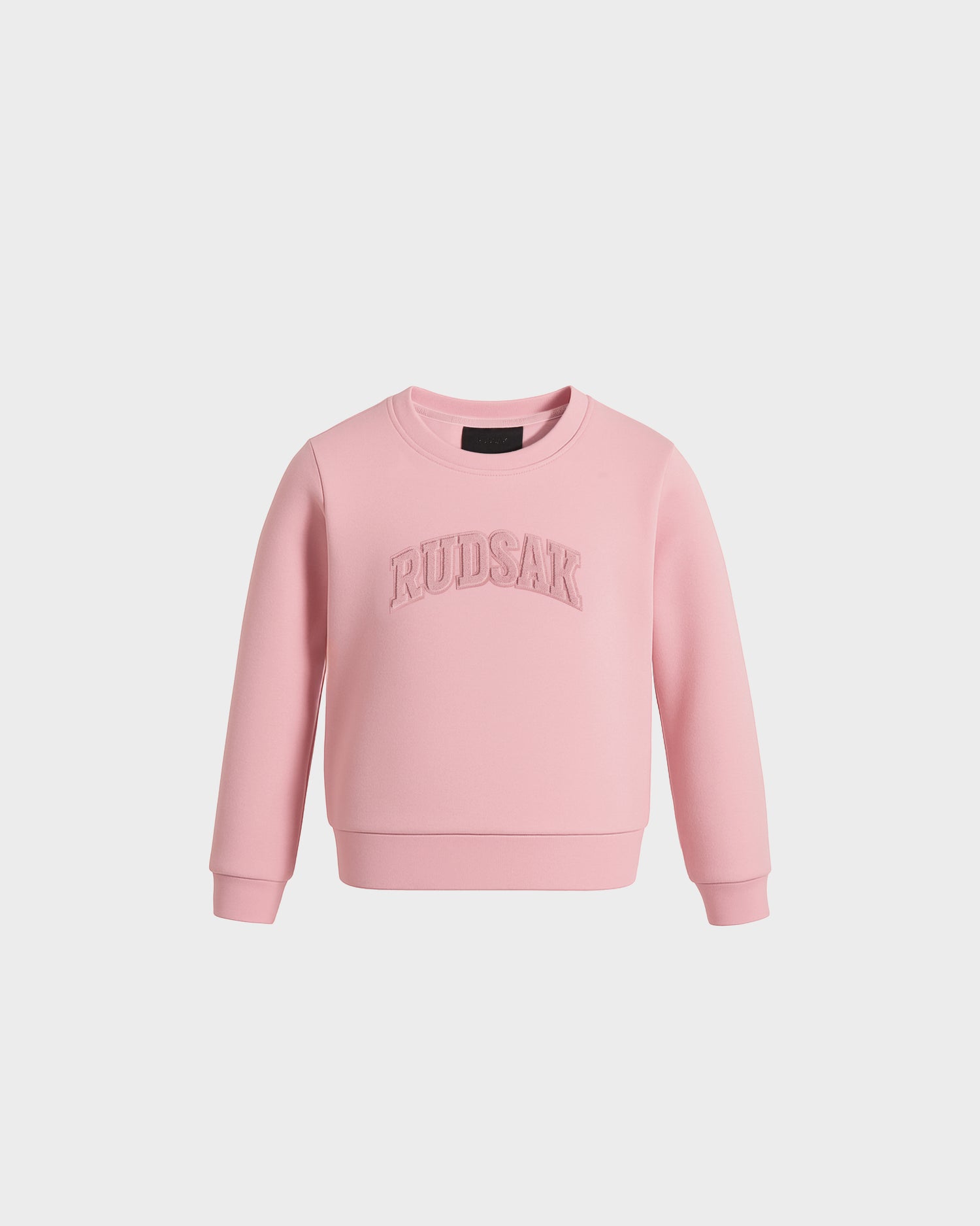 The POPPY - 1525003 Light Pink kids crewneck sweatshirt by Rudsak features long sleeves and large embroidered RUDSAK lettering on the front, made from cotton. Shown against a plain white background.