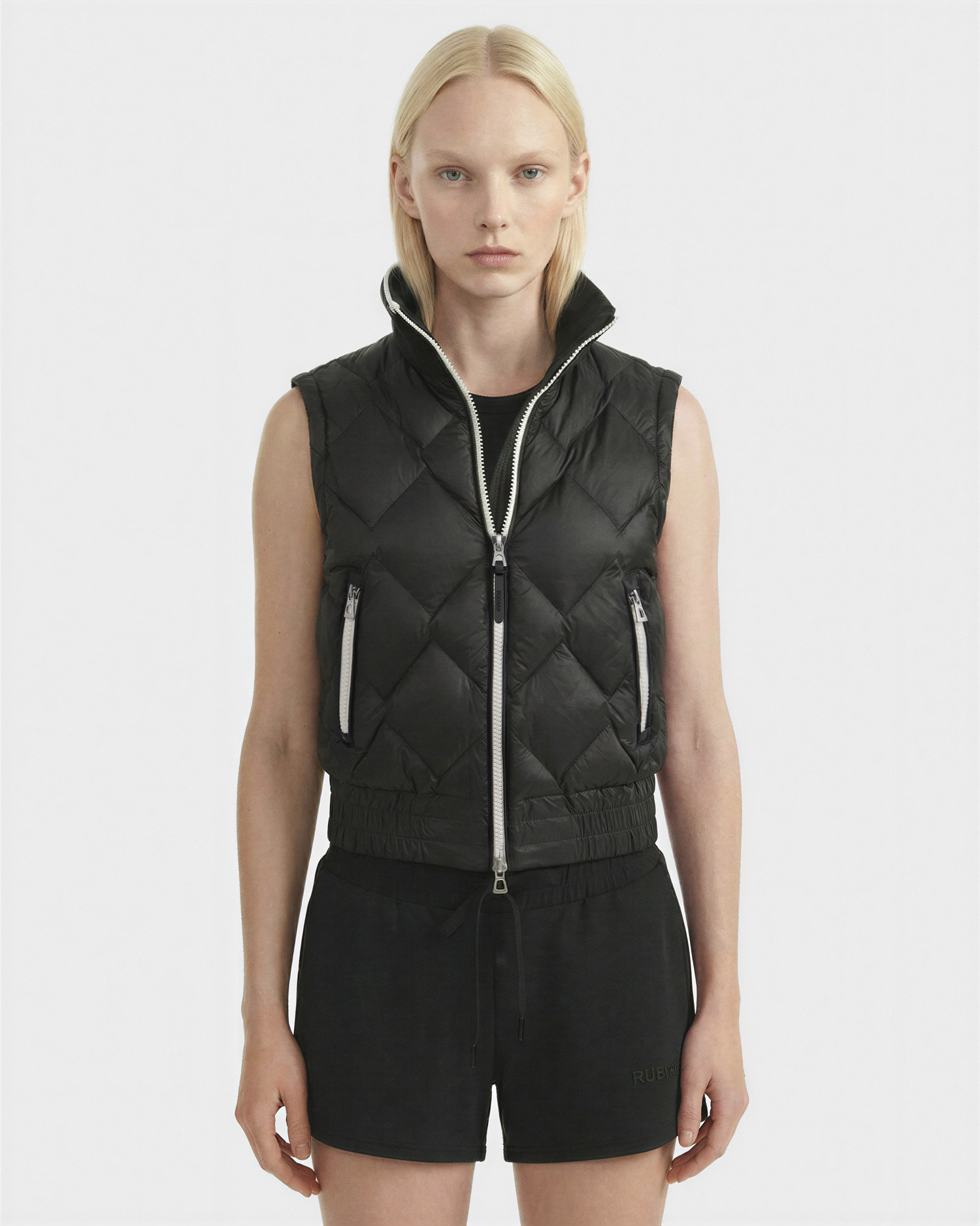 A woman wearing the Rudsak PRISA - 8126022 Black quilted vest with removable sleeves.