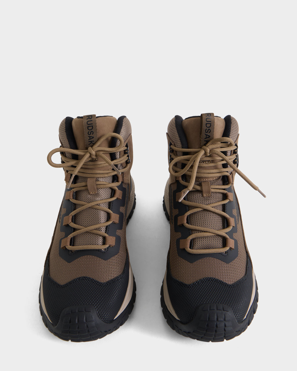 A pair of Rudsak REXON - 6226503 Cement hiking boots in brown and black with tan laces are placed side by side on a white background, displayed from a front, slightly overhead angle, blending the classic look of a winter boot with the comfort of a high-top sneaker.