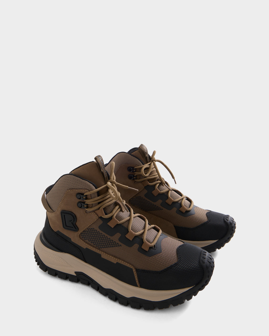 A pair of REXON - 6226503 Cement hiking boots by Rudsak, featuring a brown and black color scheme, rugged soles, tan laces, high ankle support similar to that of a winter boot, and a geometric design pattern, displayed on a plain white background.