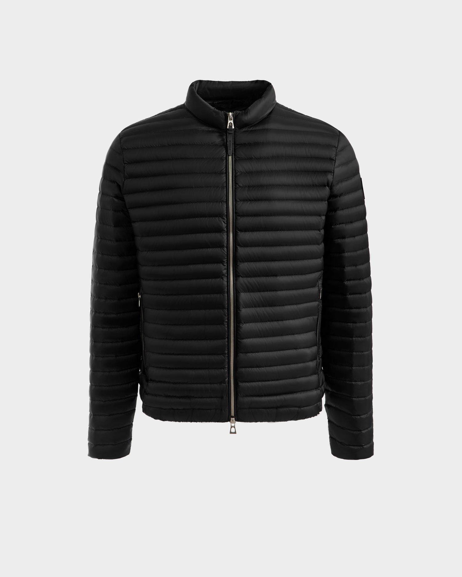The Rudsak REYMOND M - M125523 Black is a lightweight men’s down jacket with a quilted design, long sleeves, front zipper, recycled nylon shell, and RDS-certified down fill, shown on a plain light gray background.