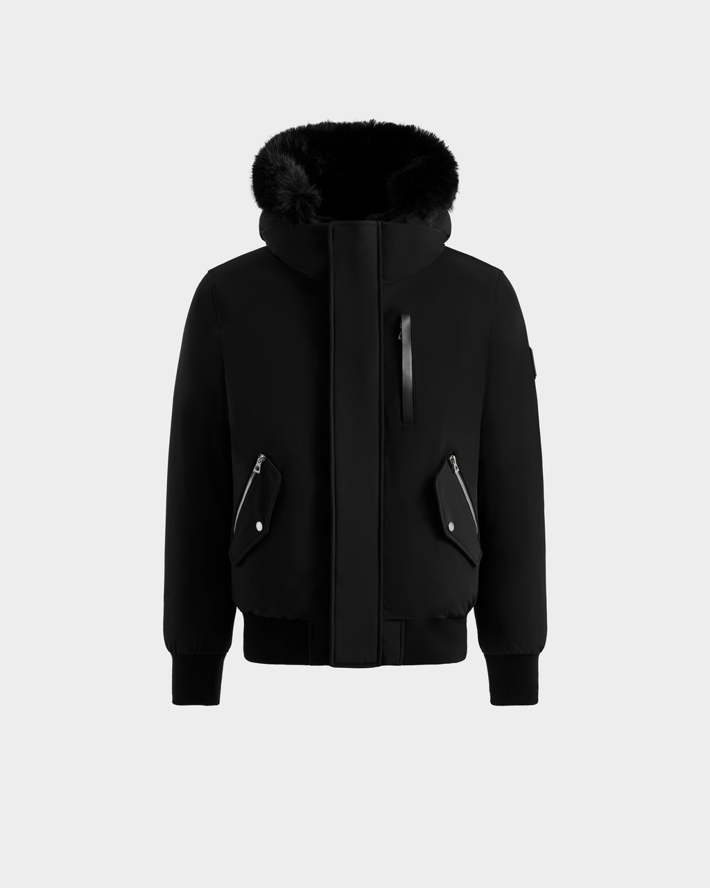 The ROCKY - 6125682 Black by Rudsak is a men’s down bomber jacket in black, crafted from recycled nylon, featuring a large furry hood, front zipper flap, zippered side and chest pockets with flaps, plus ribbed cuffs and hem—shown on a plain light background.