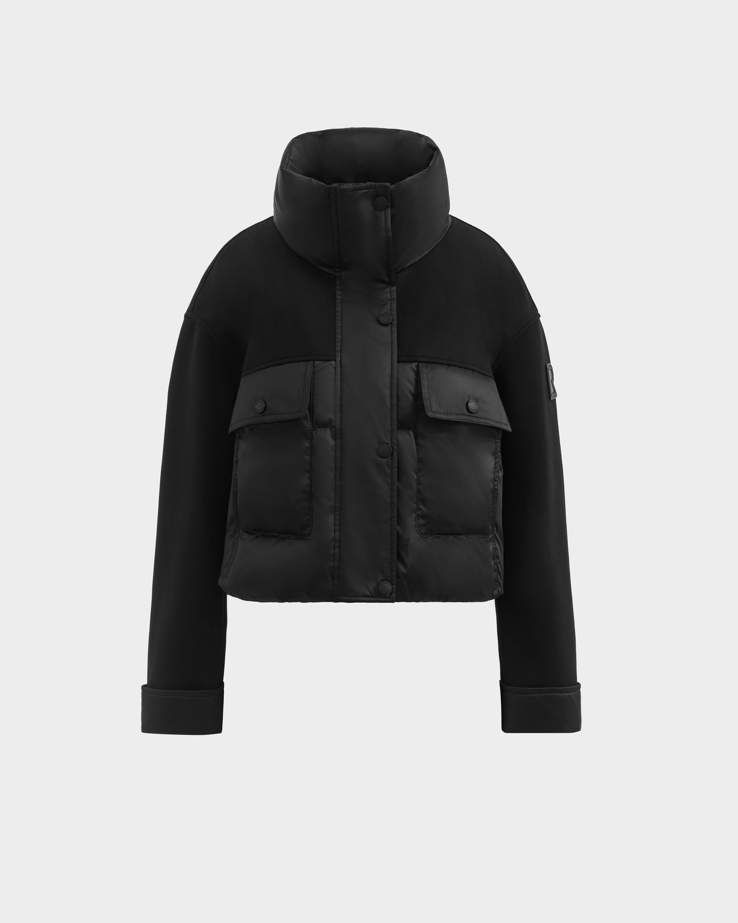 The ROME - 8126028 Black by Rudsak is a modern black cropped jacket with a high collar, long sleeves, two large front pockets, snap buttons, and a sleek quilted down-filled finish for a stylish look.