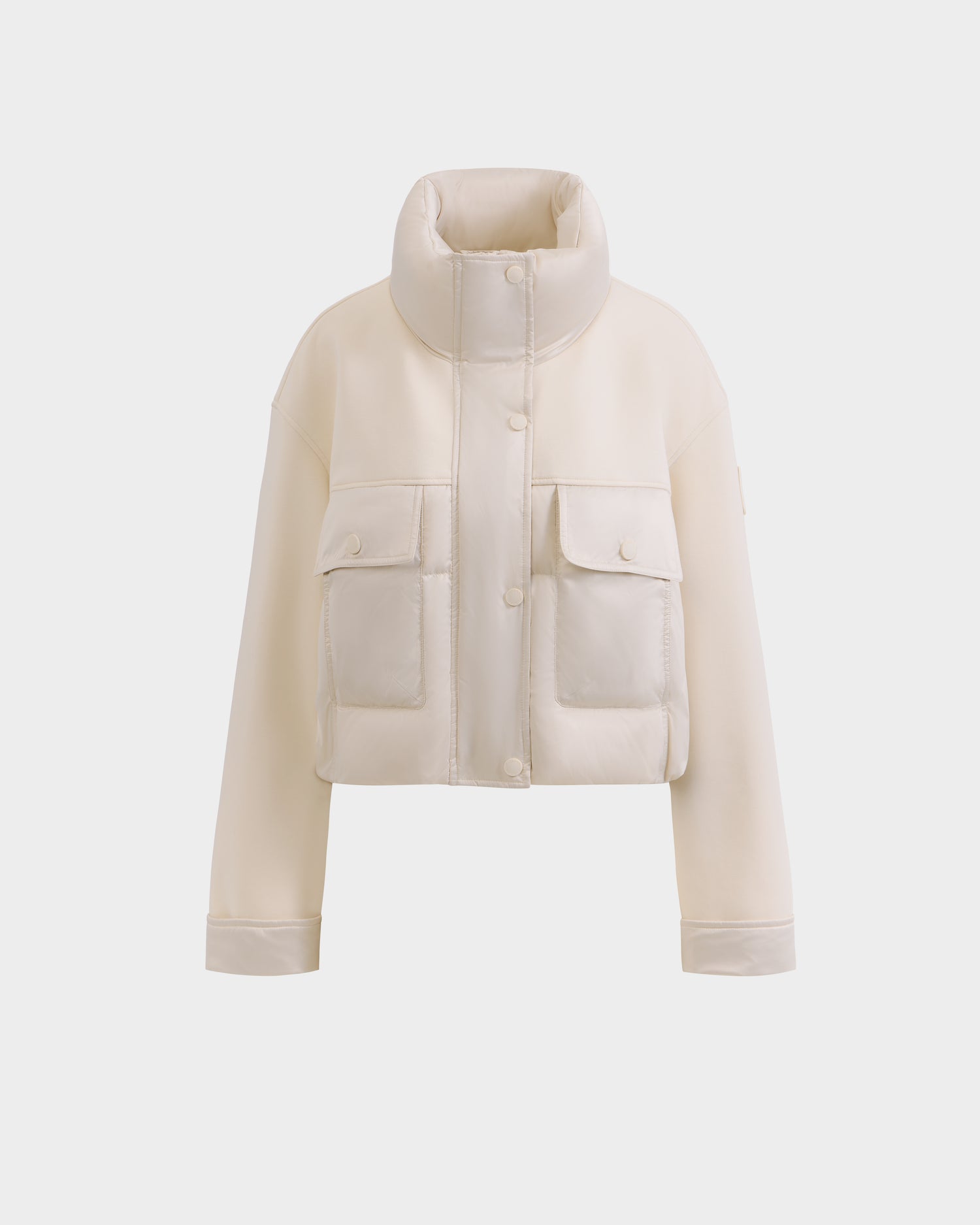 The Rudsak ROME - 8126028 Iceland is a cream cropped quilted down puffer jacket featuring a high collar, snap buttons, long sleeves, and two large front pockets for lightweight warmth. Displayed on a plain white background.