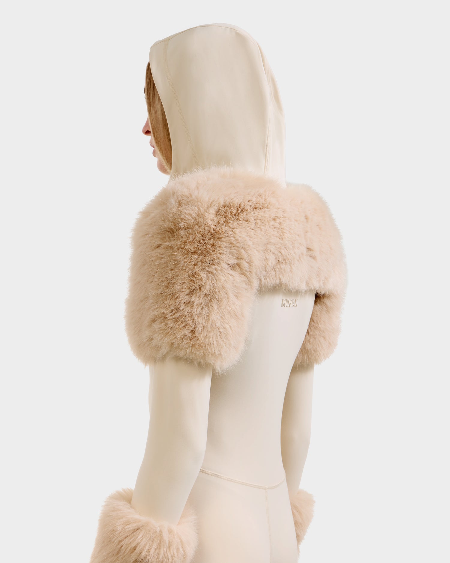A person is shown from the back wearing the Rudsak MYLA - 8525671 Vanilla: a cream-colored hooded outfit with plush, beige faux fur accents on the shoulders and forearms, set against a plain white background.