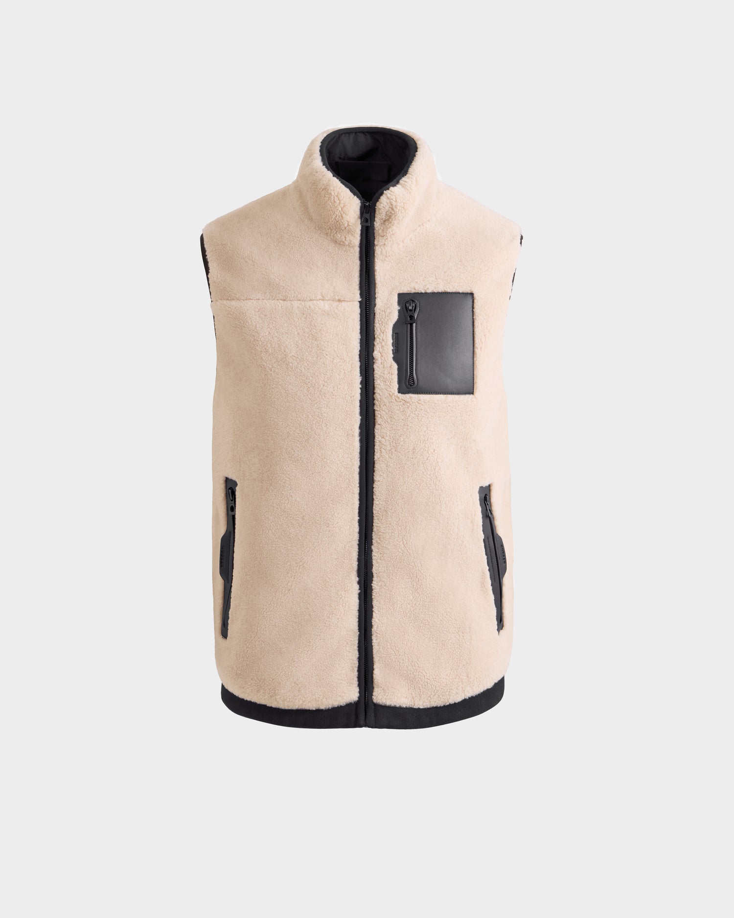 The Rudsak RUMMY - U524502 Vanilla M is a beige unisex teddy vest with black trim, two zippered side pockets, and a black zippered chest pocket, shown against a plain light gray background.
