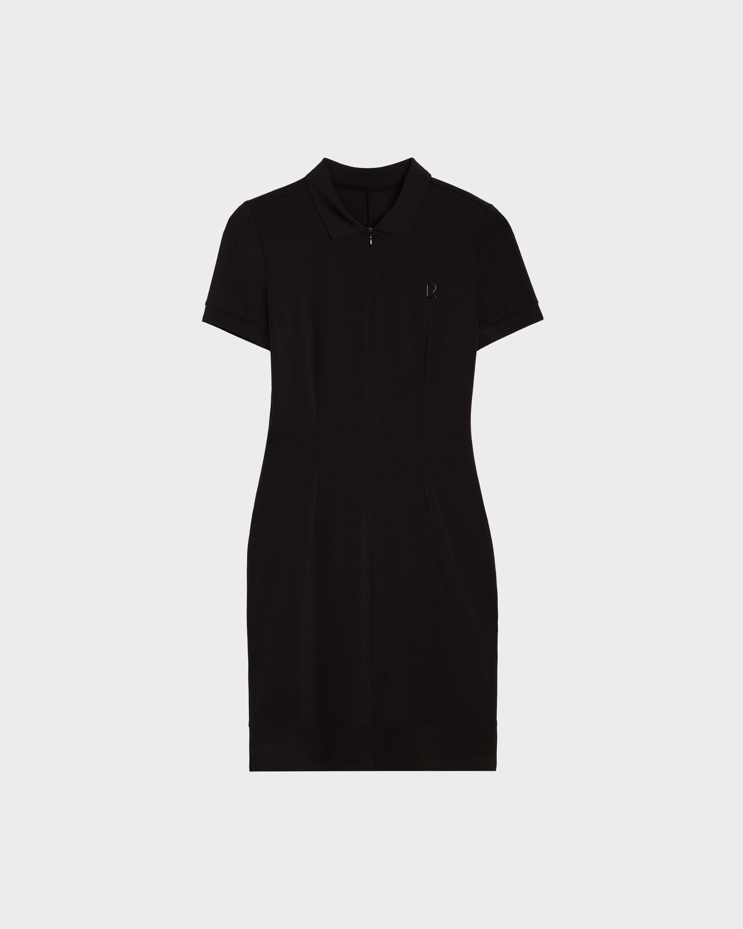 The SUKI - 8524029 Black by Rudsak is a women’s short-sleeved, knee-length polo dress with a collar and zippered front, blending sporty elegance, shown against a plain white background.