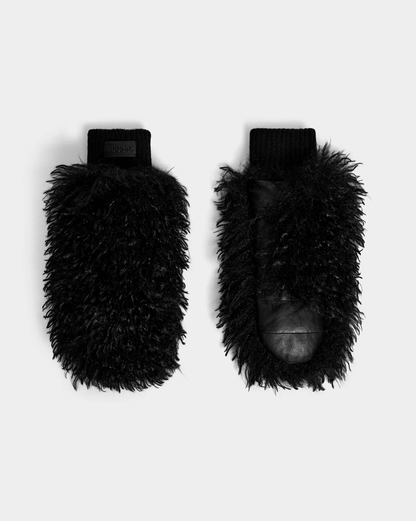 The SUSAN M - 8424505 Black faux Mongolian fur mittens by Rudsak feature a fluffy, curly texture and ribbed knit cuffs—a stylish après-ski accessory, shown side by side on a plain white background.