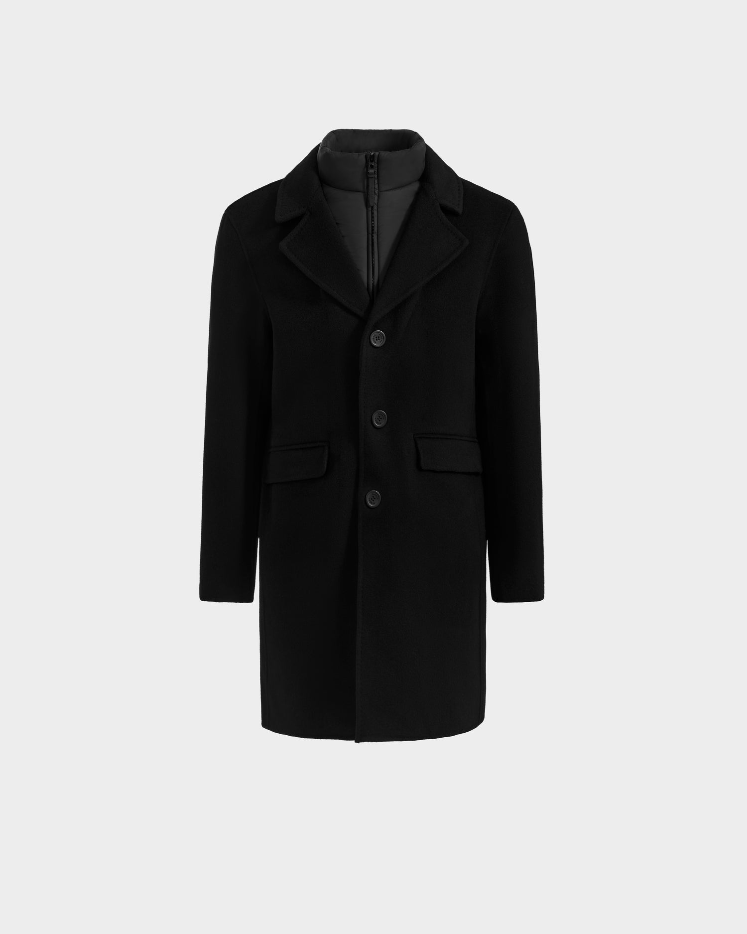 The SAWYER - 6125511 Black men’s coat by Rudsak features a notched collar, front buttons, flap pockets, and an inner padded lining. This black, knee-length wool blend coat is shown on a plain light gray background.