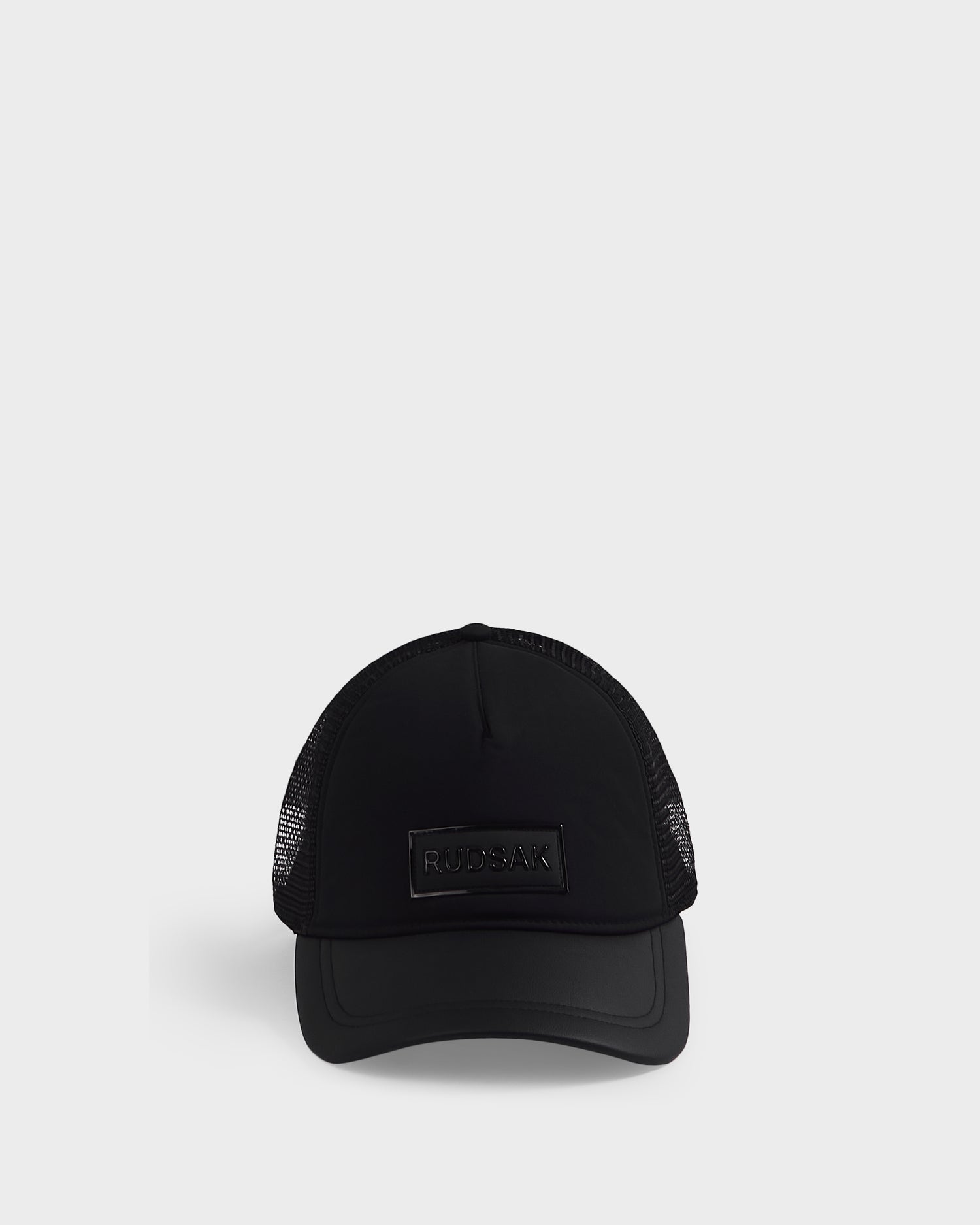 The Rudsak FENIX - 9422522 Black is a black mesh-back baseball cap featuring a rectangular logo patch on the front, shown against a light gray background.