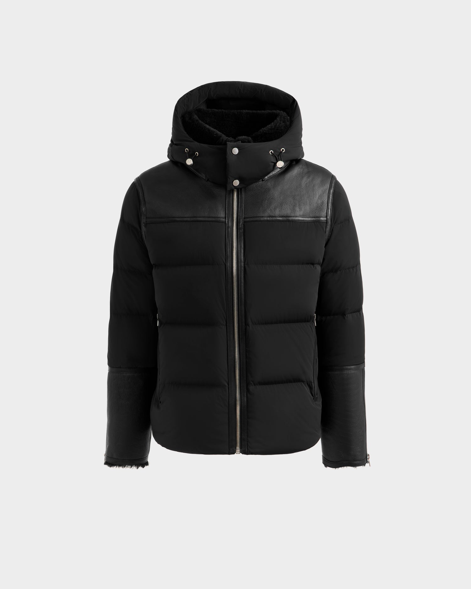 The Rudsak SIMON - 6125597 Black is a men's quilted down puffer jacket with a hood, front zipper closure, leather accents on the shoulders and sleeves, and metal snap buttons on the collar, shown against a plain light gray background.