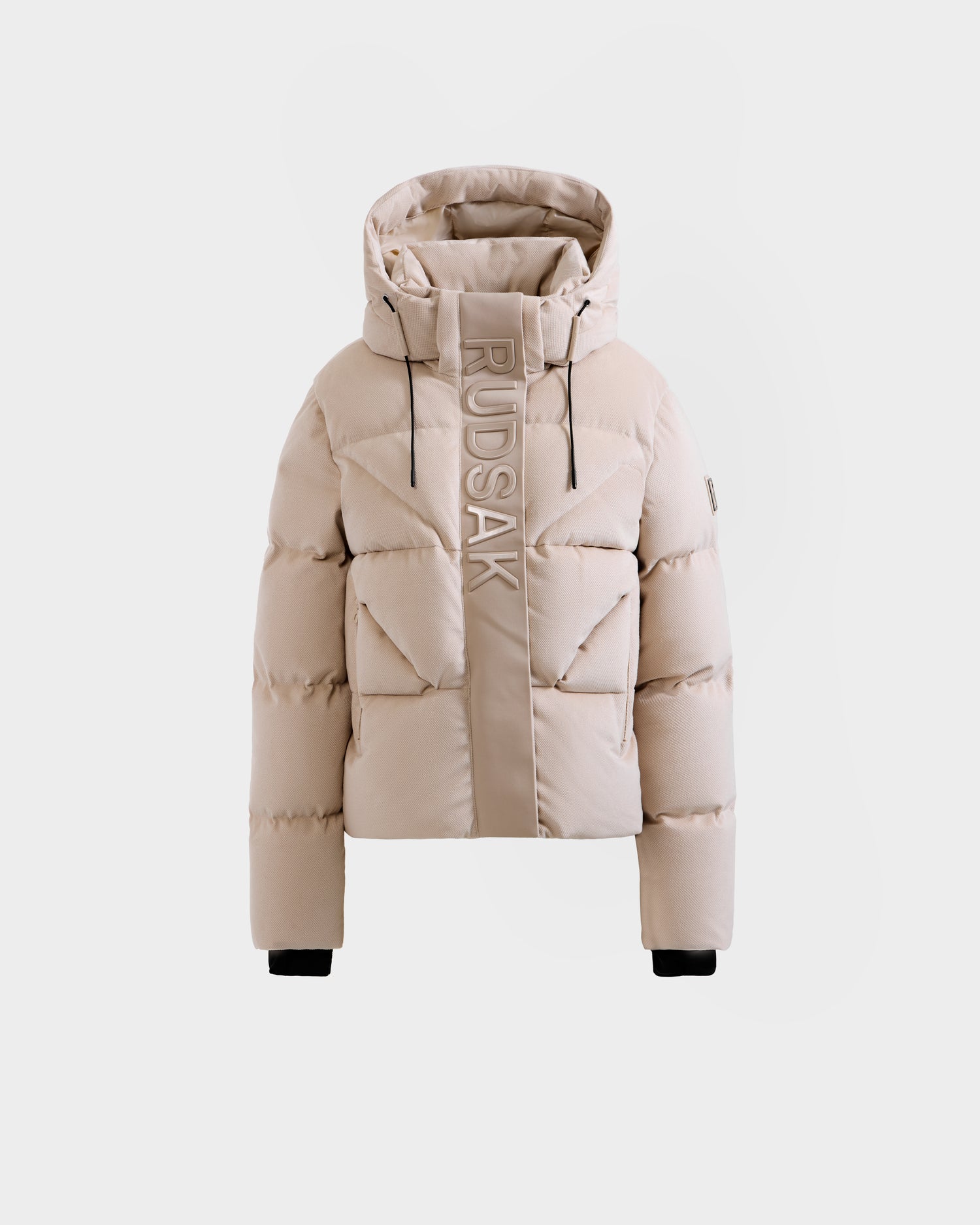 The Rudsak STEFANIE V - L125584 Vanilla is a beige down puffer winter coat with a hood, black cuffs, and "RUDSAK" vertically printed on the front, shown against a plain white background.