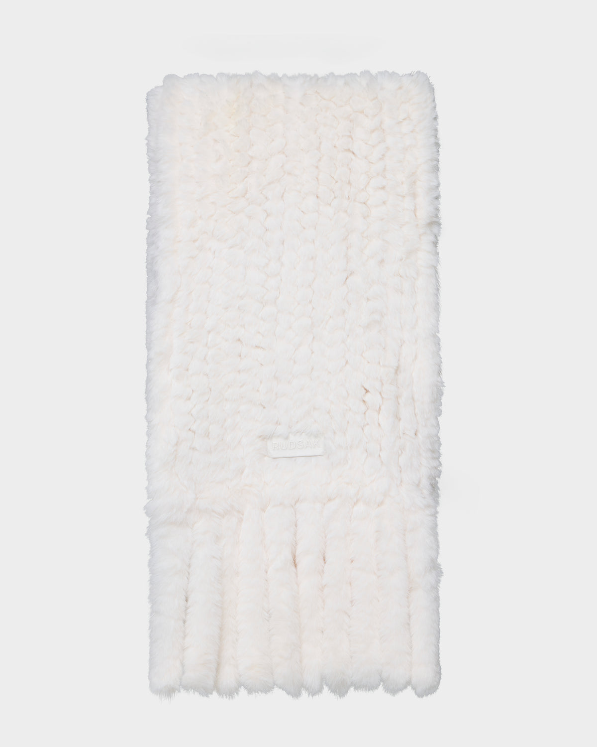 The Rudsak TAVIA - 8426511 Vanilla is a soft, white, knitted scarf with a fluffy texture and ribbed ends, shown neatly folded on a plain white background.