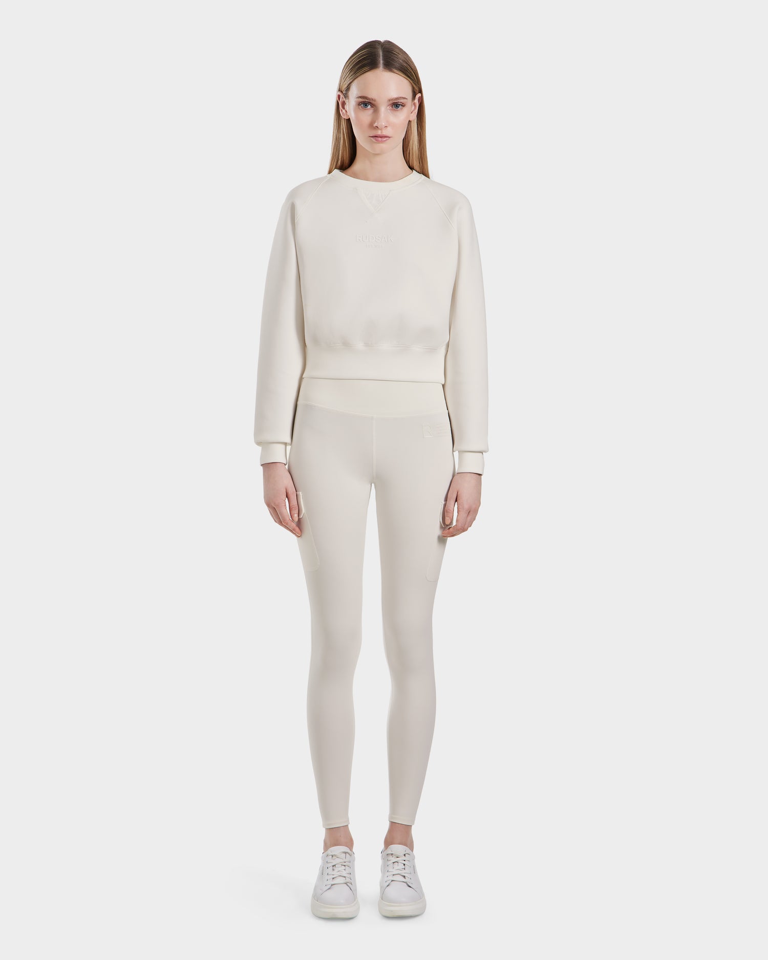 A woman faces forward, wearing the Rudsak BETSY - 8525087 Iceland premium cotton blend women's crop sweater with matching leggings and white sneakers, set against a plain white background.