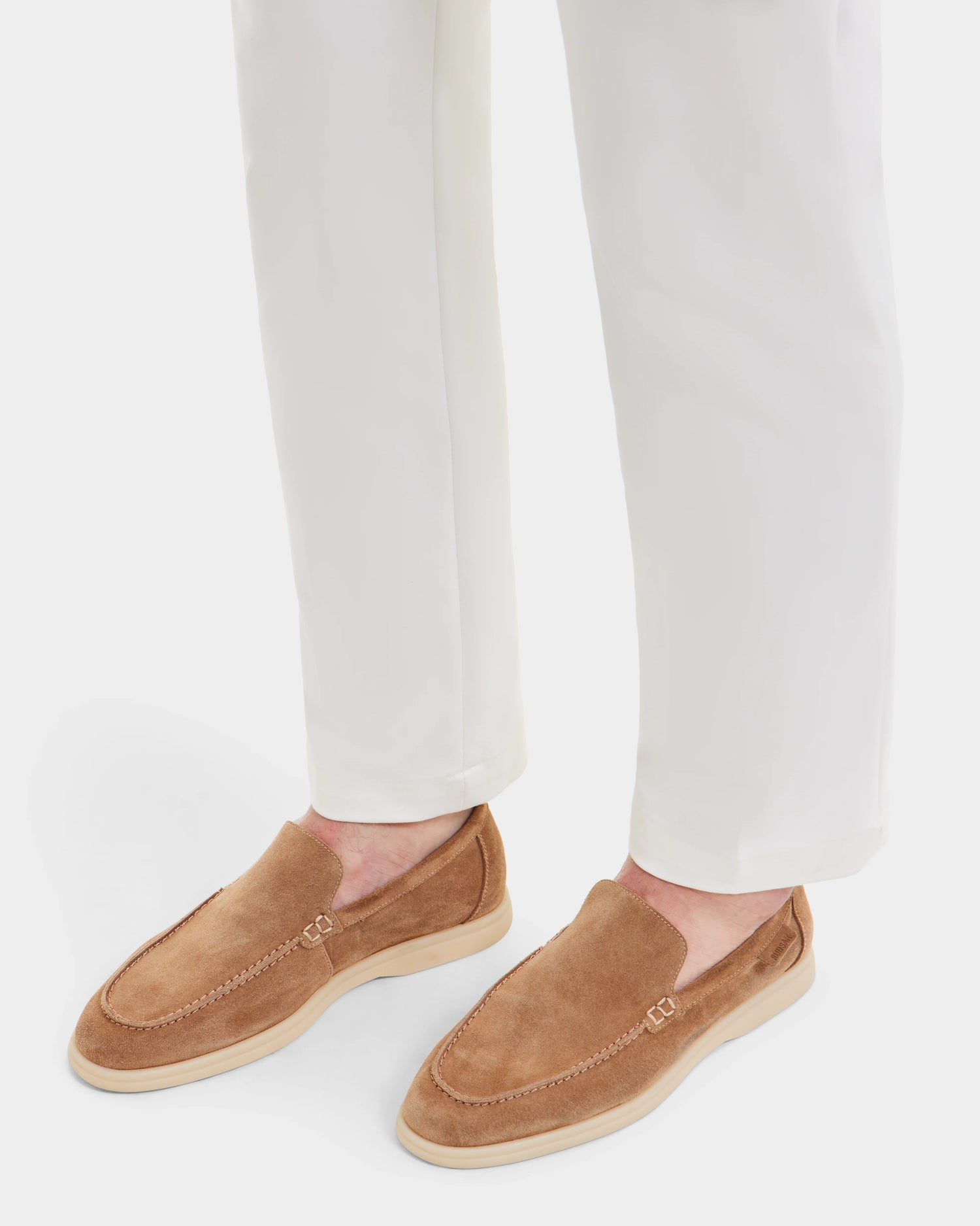 A person wears white pants and Rudsak CHANNING - 6225005 Almond men’s loafers in light brown suede with light soles, standing on a white background.