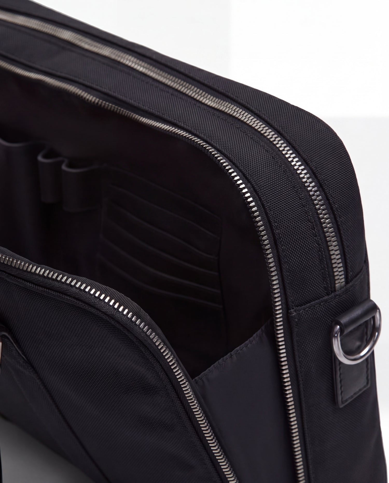 A close-up of the Rudsak HENRY N - 9326056 Black bag shows its zippered design with an open pocket, revealing interior slots for organizing small items.