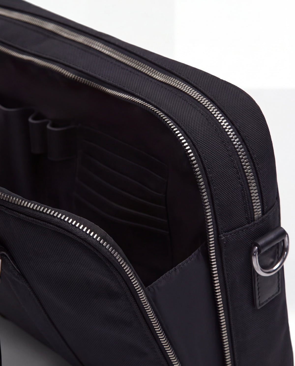 Close-up of the Rudsak HENRY N - 9326056 Black bag featuring a zippered pocket partially open to reveal organized interior compartments and slots.