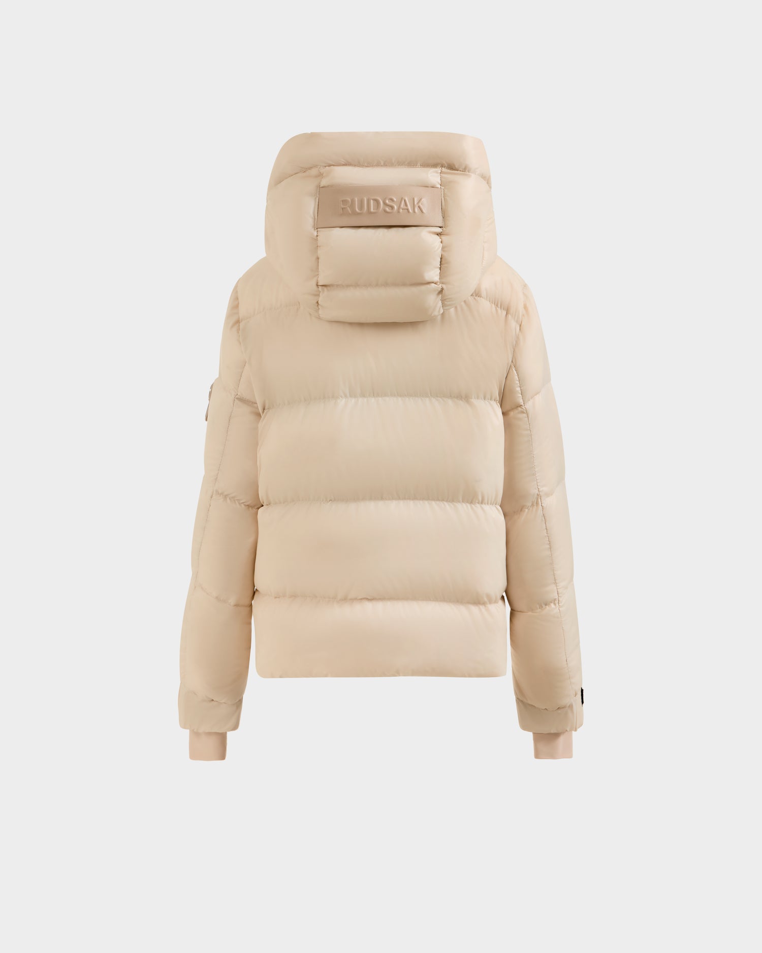 The Rudsak VINCE KS - 0124502 Vanilla is a beige unisex puffer jacket with a hood made from RDS-certified down. Viewed from the back, it has horizontal stitching, ribbed cuffs, and RUDSAK branding on the hood against a white background.