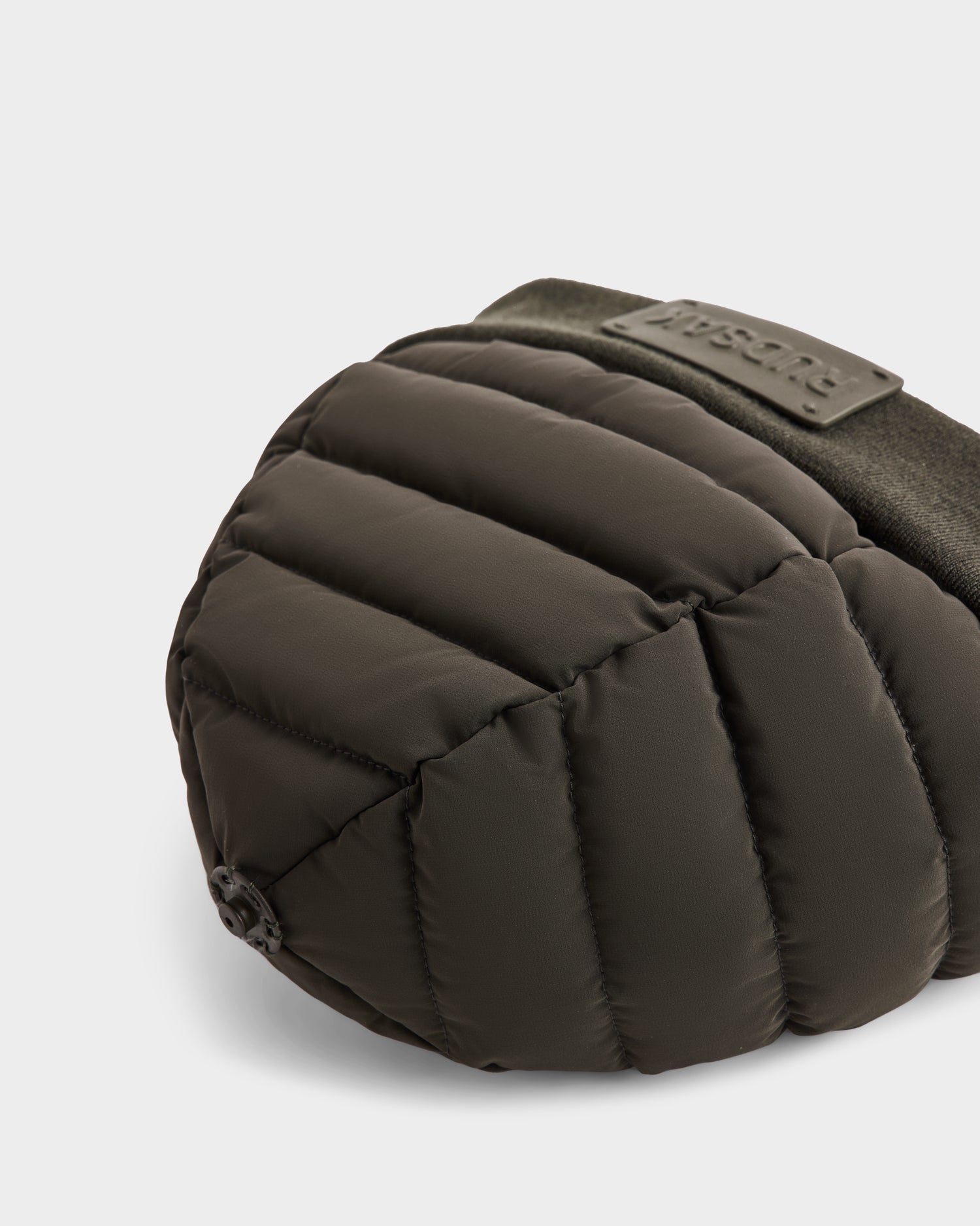 A close-up of the Rudsak GALA - 8424514 Dark Olive bag, styled with a cozy womens quilted down puffer hat topped with a faux fur pom pom.