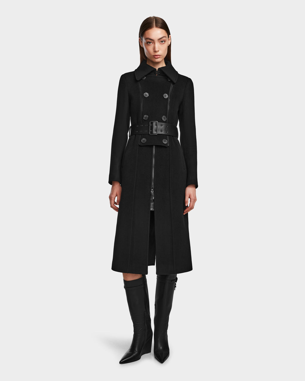 A woman with straight brown hair and a neutral expression stands facing forward in the Rudsak VIRGINIE - 8124696 Black, a women’s double-breasted wool-cashmere peacoat with a wide belt and knee-high boots, set against a plain white background.