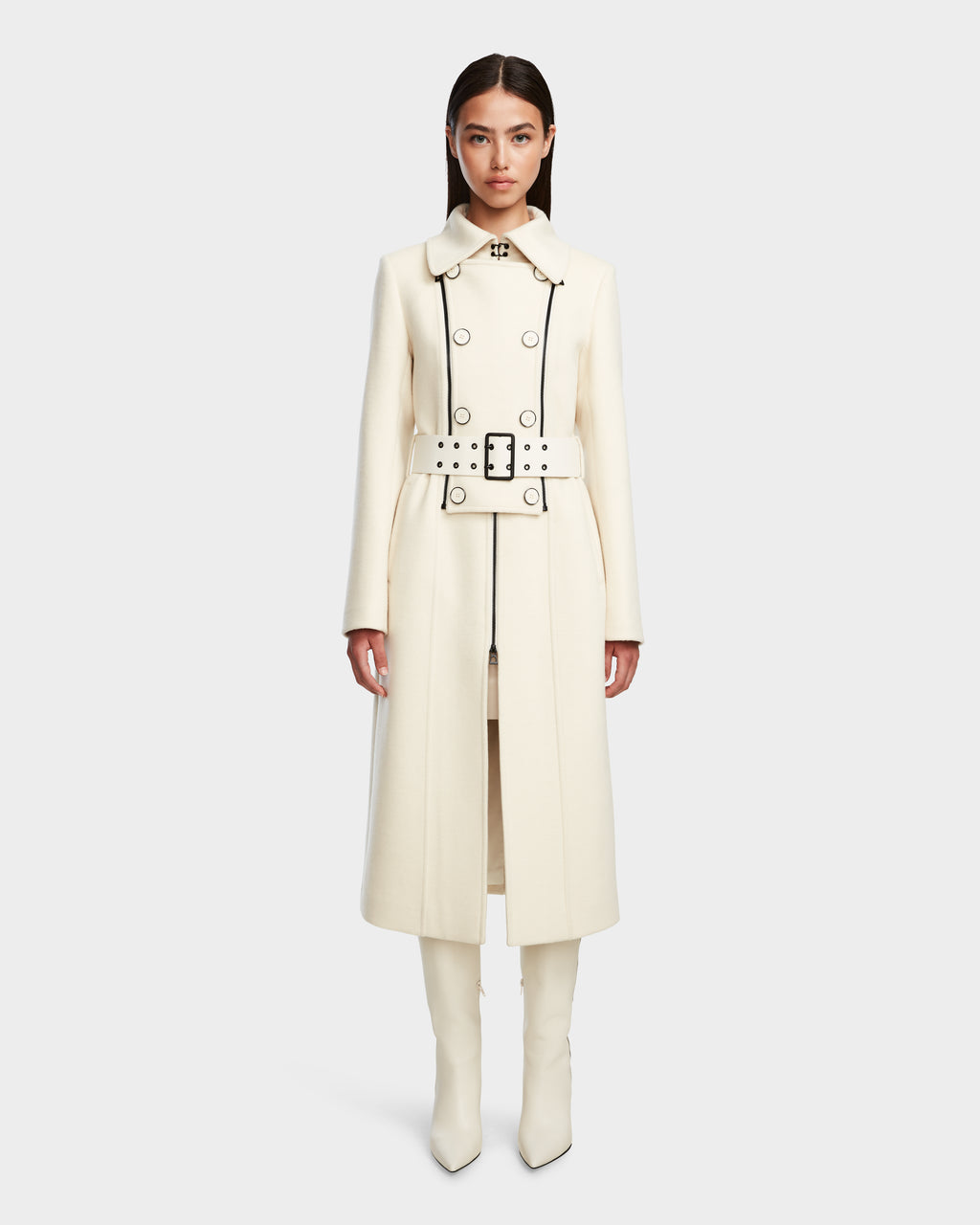 A woman stands facing forward in the VIRGINIE - 8124696 Iceland peacoat by Rudsak, featuring black buttons, a matching wide belt, a removable faux fur collar, and paired with cream knee-high boots against a plain white background.