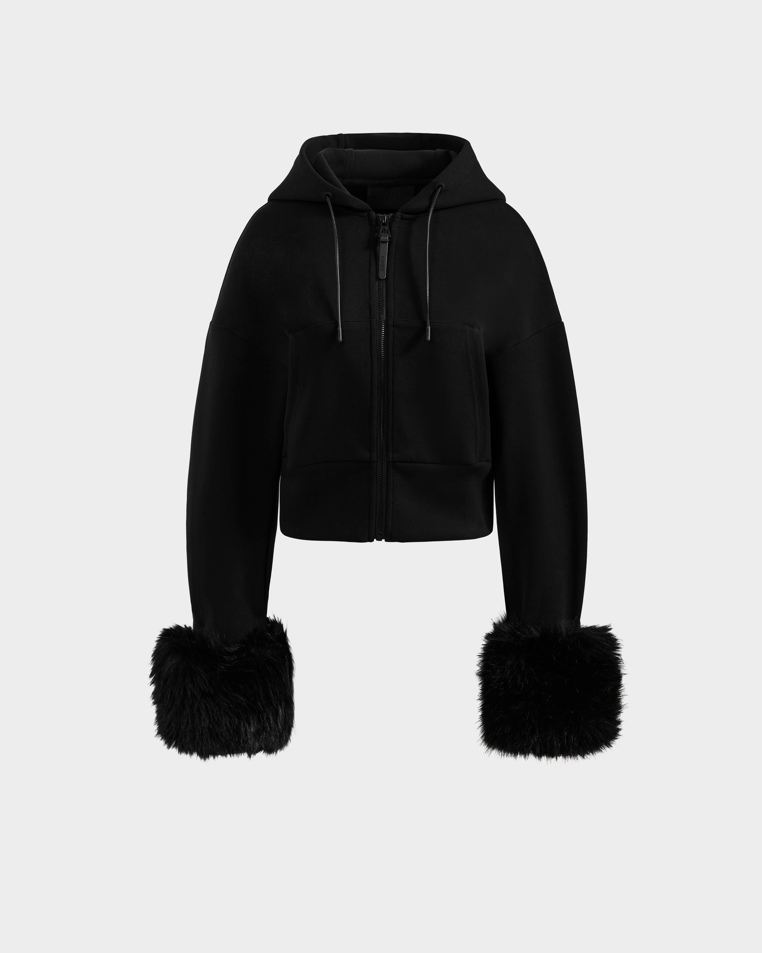 The Rudsak ZILLIA - 8525673 Black is a women's cropped zip-up hoodie with a front zipper, drawstrings, and statement faux fur sleeve cuffs, shown on a plain light gray background.