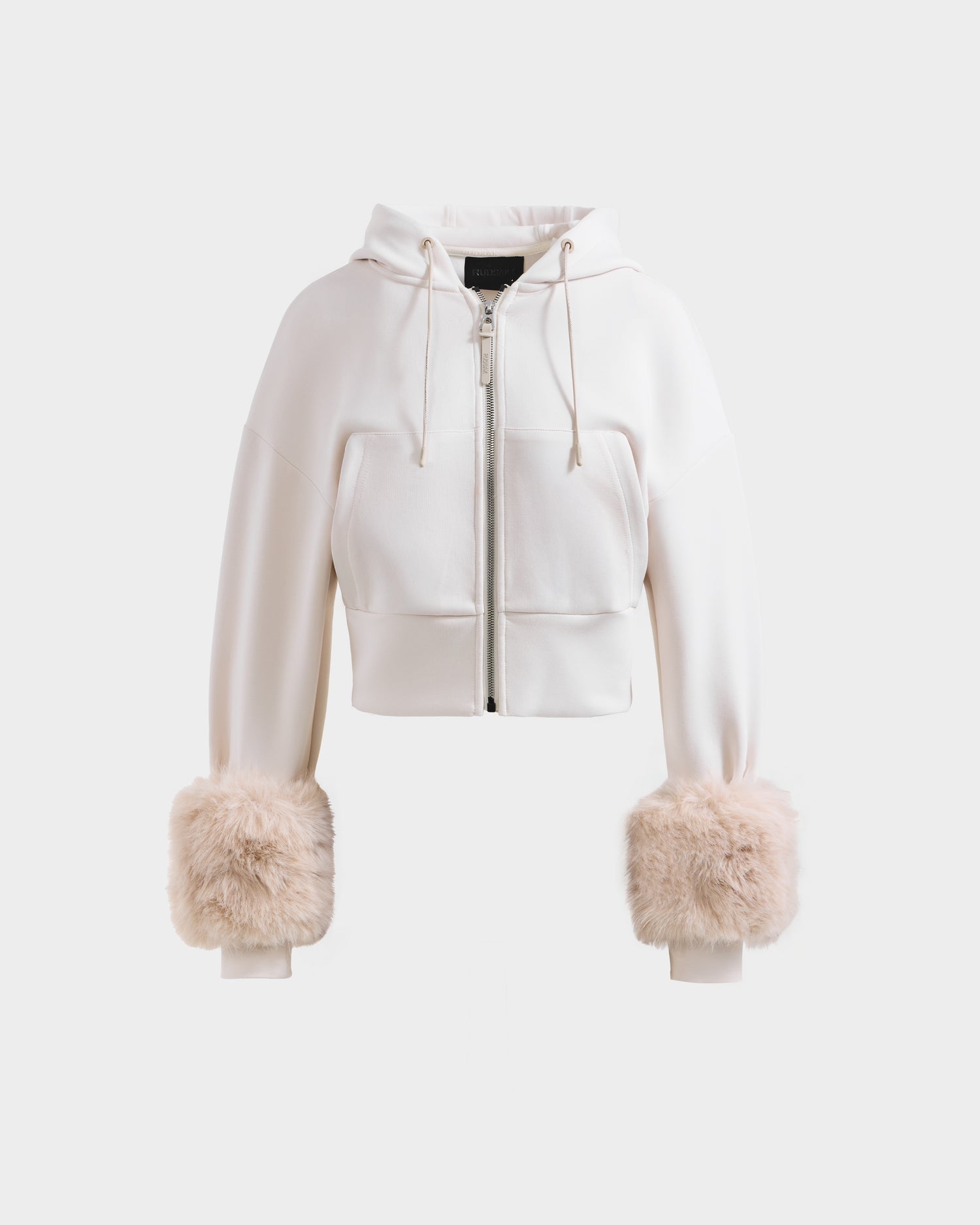 The Rudsak ZILLIA - 8525673 Vanilla is a women’s streetwear cropped zip-up hoodie with front zipper, drawstrings, and large beige faux fur cuffs on the sleeves, shown against a plain white background.