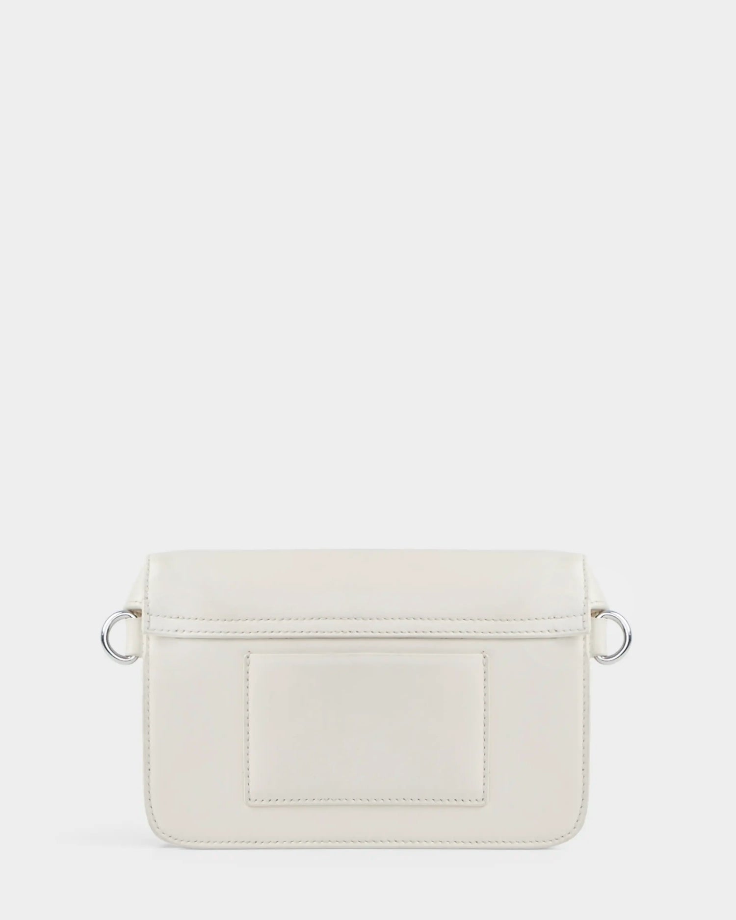 A small, rectangular, eggshell women’s leather crossbody bag—the CAMELIA - 8324000 by Rudsak—features a front patch pocket, silver side rings, and minimal stitching, shown on a plain white background.