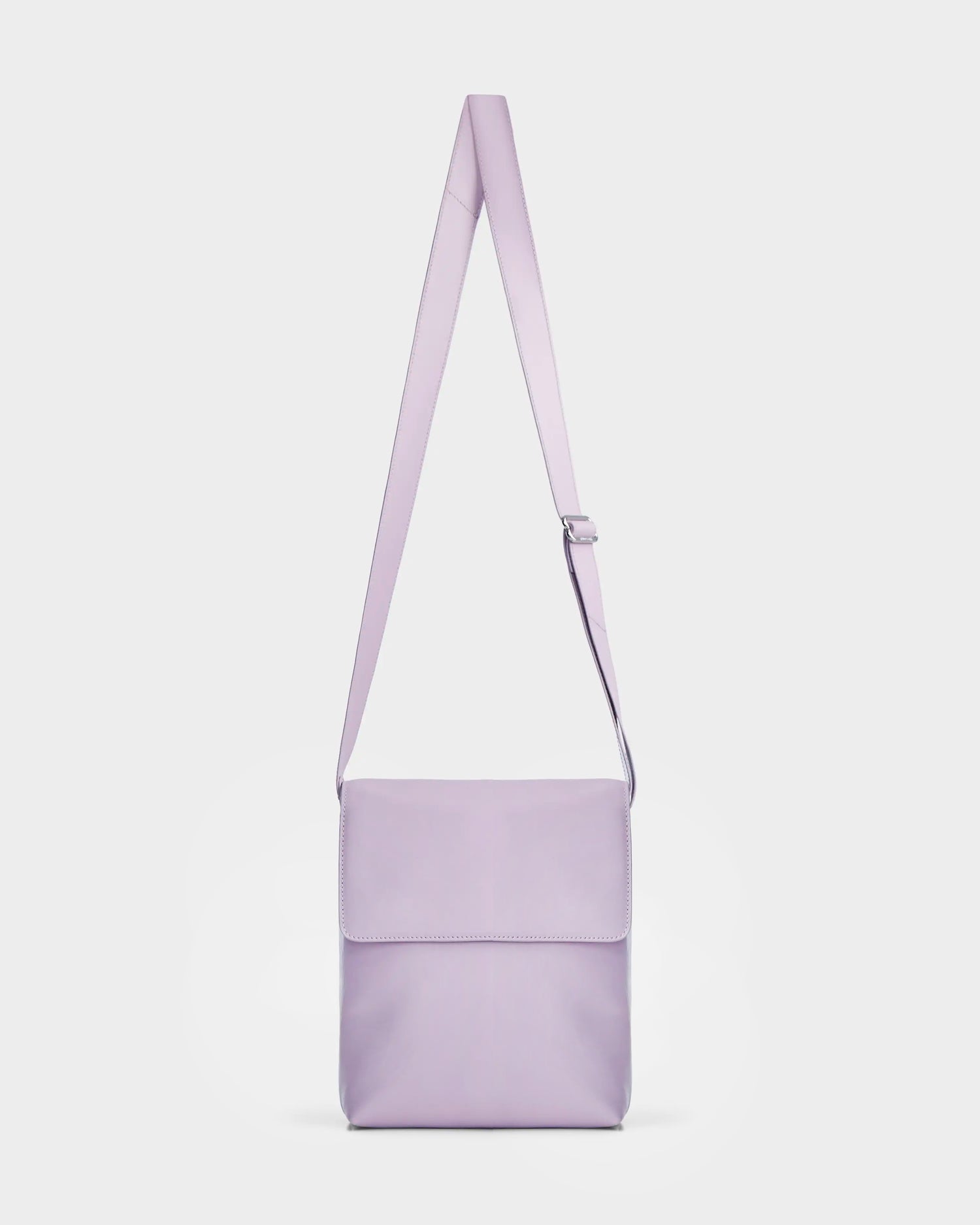 The Rudsak MADDY - 8319536 Lilac Foam is a light purple leather messenger bag with a minimalist design, flap closure, and adjustable strap, shown against a white background.