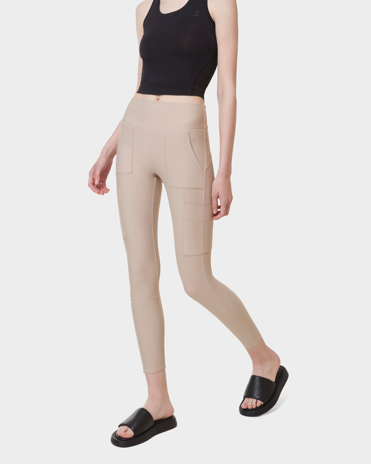 A person stands against a plain white background wearing Rudsak's ADELLE - L523032B Cream high-waisted leggings with side pockets.