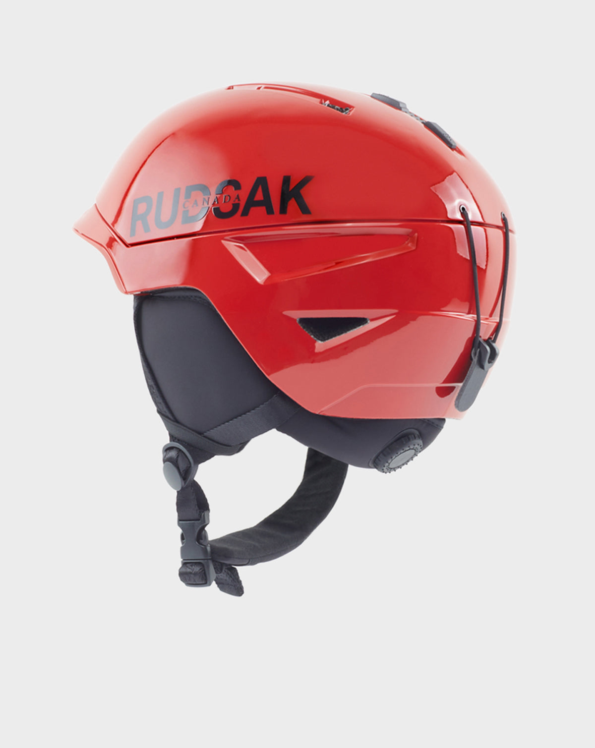 The Rudsak RACE - 9421514 POPPY RED ski helmet features a bright red gloss finish with black ear pads and chin strap, and displays the brand name on the side as part of the exclusive Ski Capsule Collection.