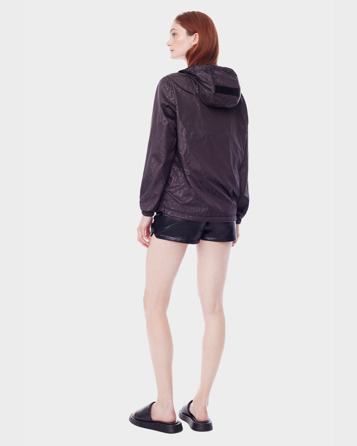 A person with light skin and long straight auburn hair faces away, wearing the RUDSAK NICKY - 9123005 BLACK F reversible lightweight jacket against a plain white background.
